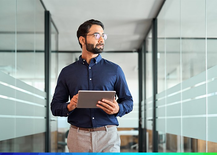 Man walking through office holding tablet device