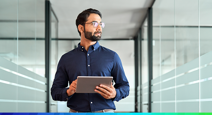 Man walking through office holding tablet device